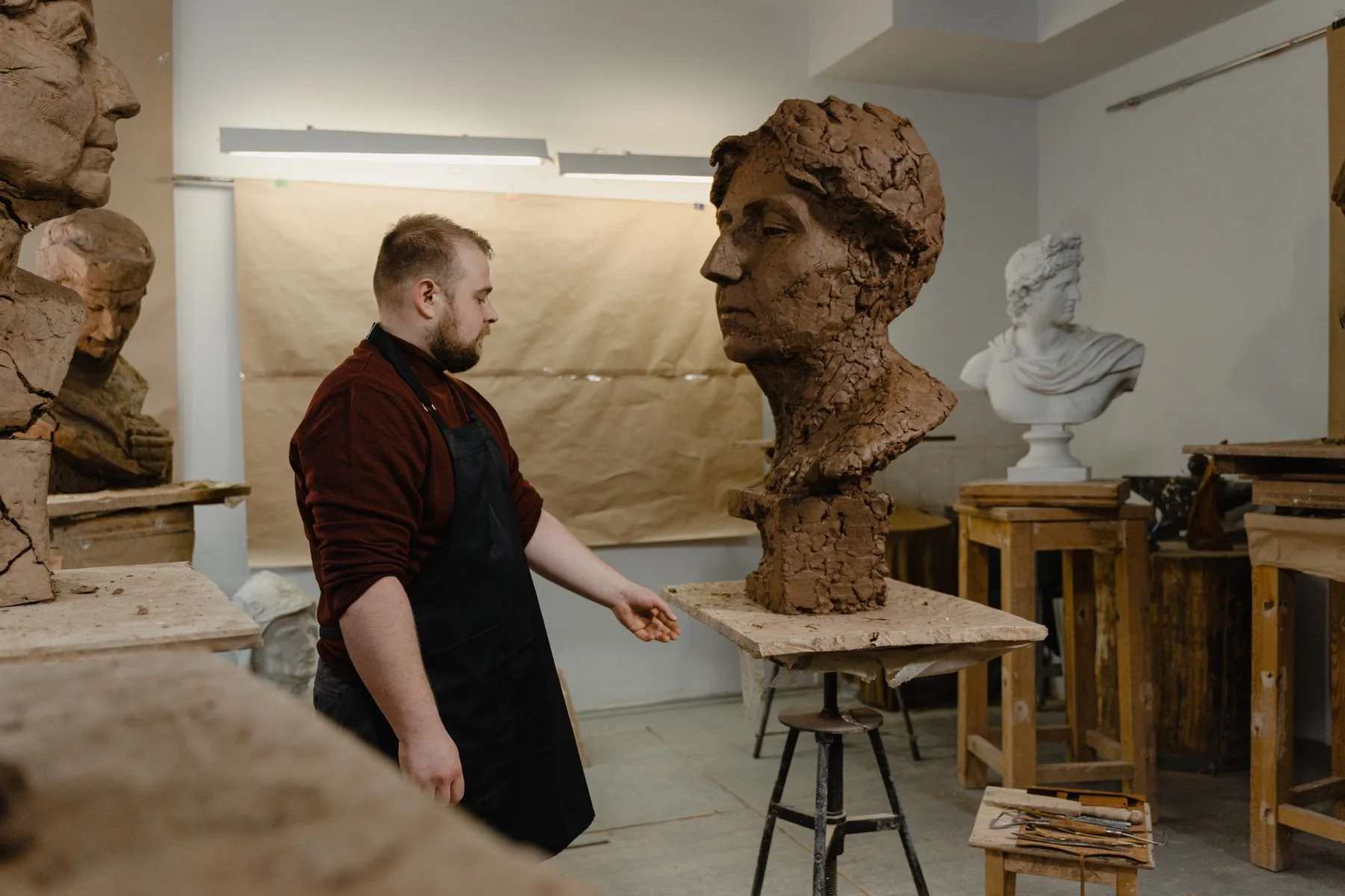 Sculptor at work on a clay bust in the studio