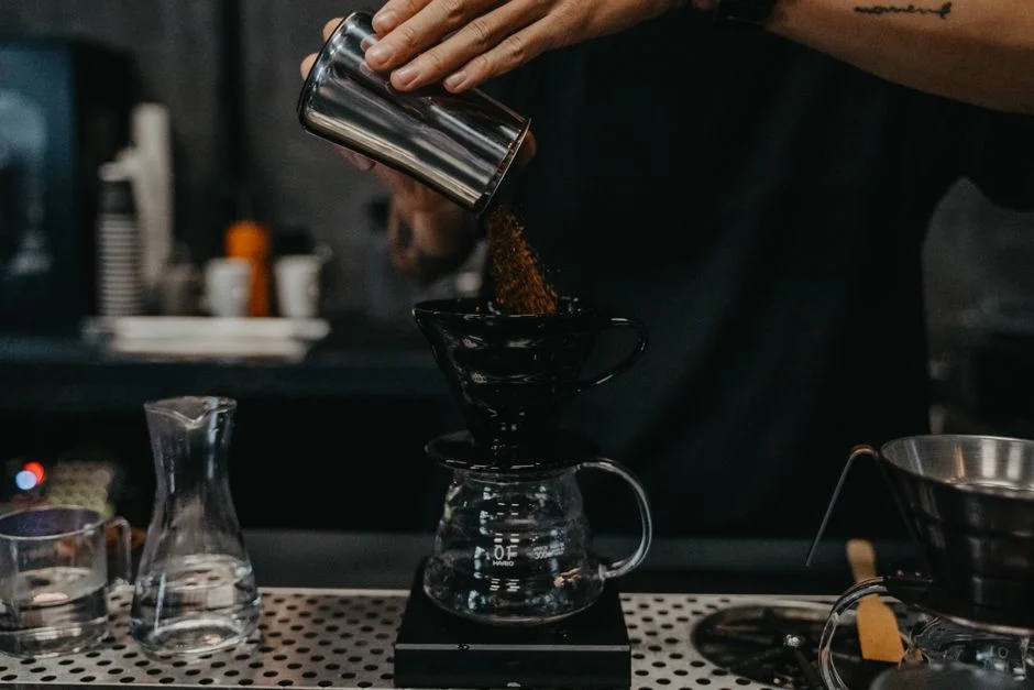 A barista pouring hot water over a pour-over dripper
