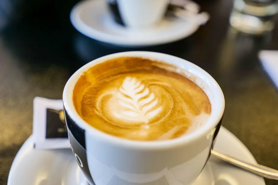 A latte with leaf-pattern art on a wooden table