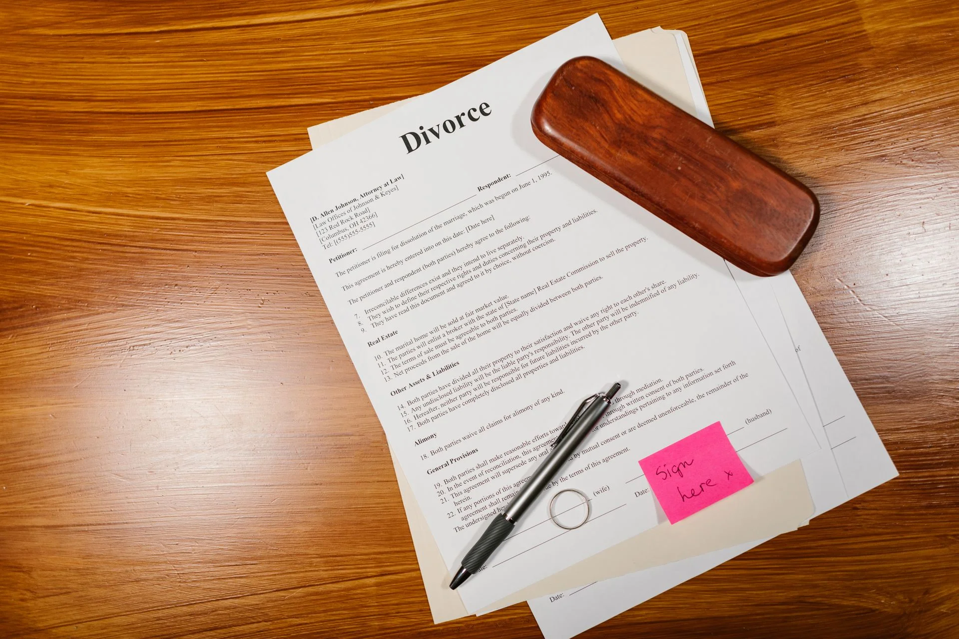 Divorce papers, a pen and a wedding ring on a wooden desk
