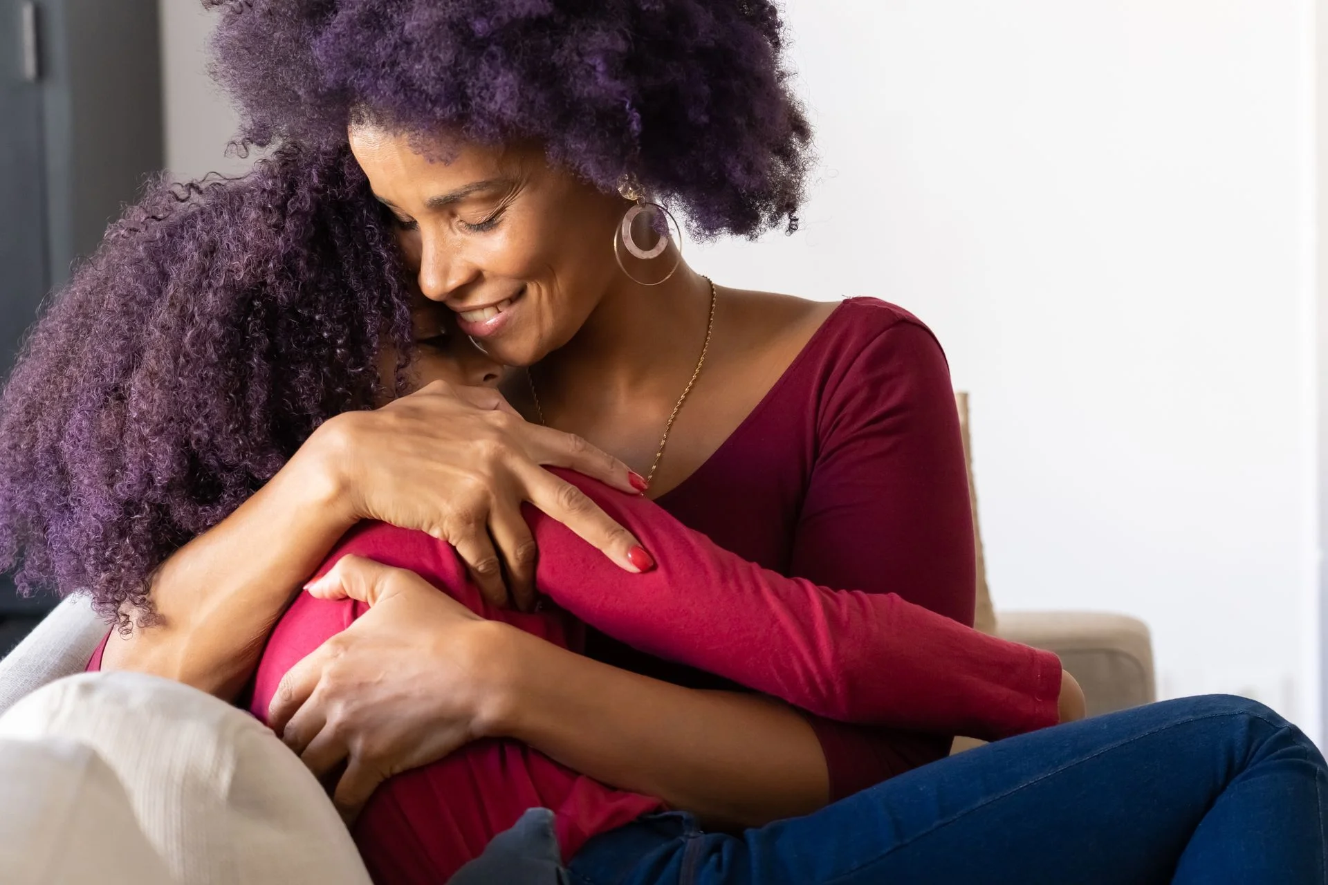 A mother hugging her daughter on the sofa at home