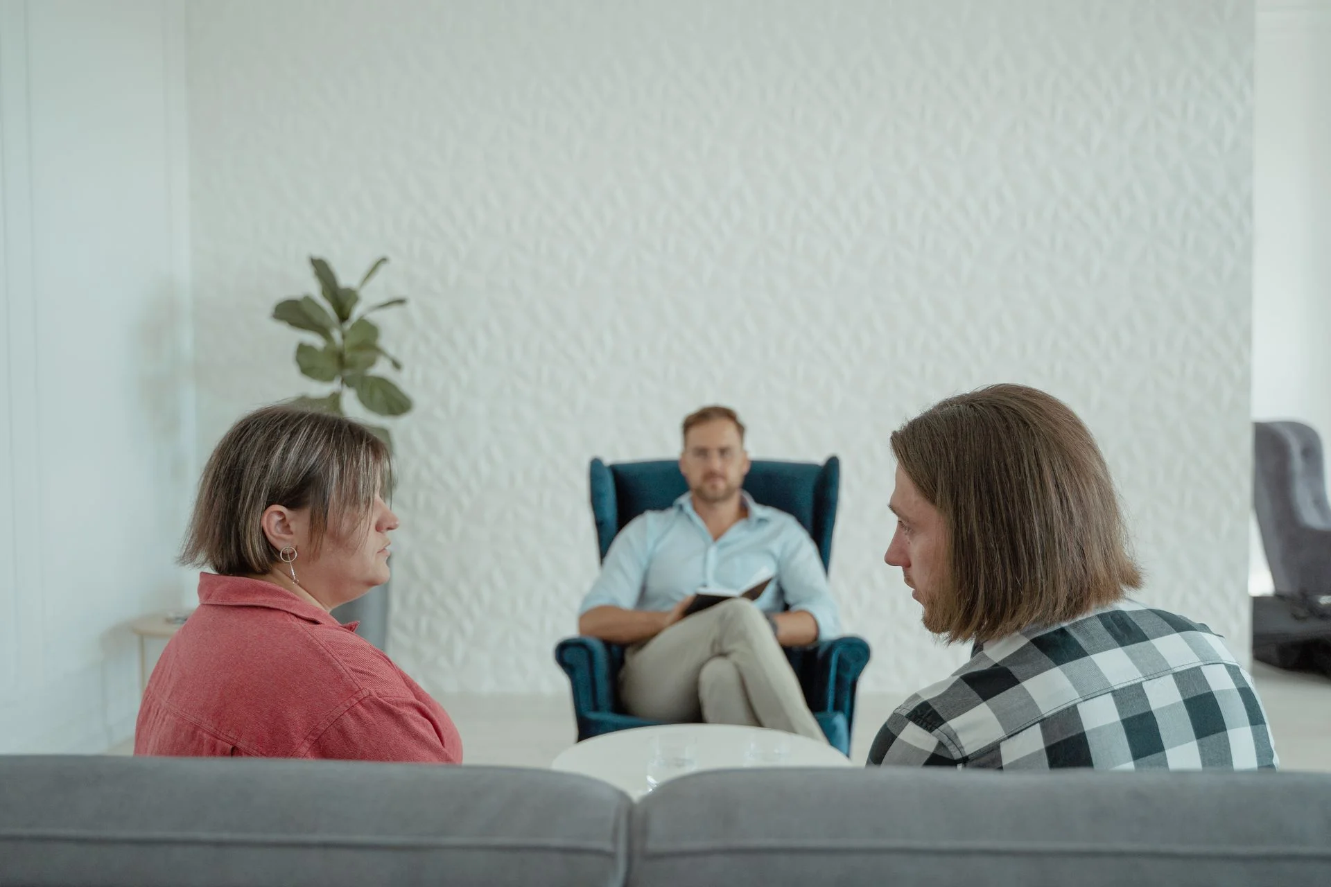 A couple talking with a mediator in a bright, quiet room