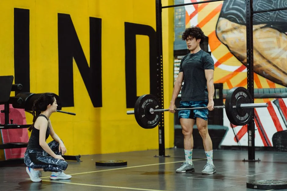 Member squatting a barbell under a coach’s eye