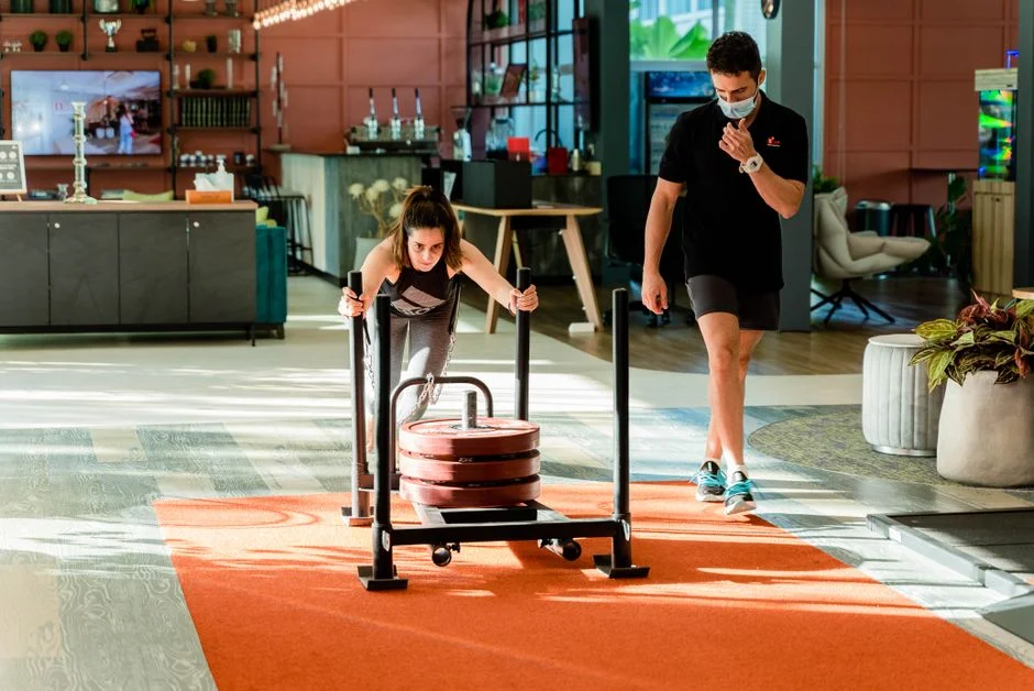 Member pushing a weighted sled across the turf