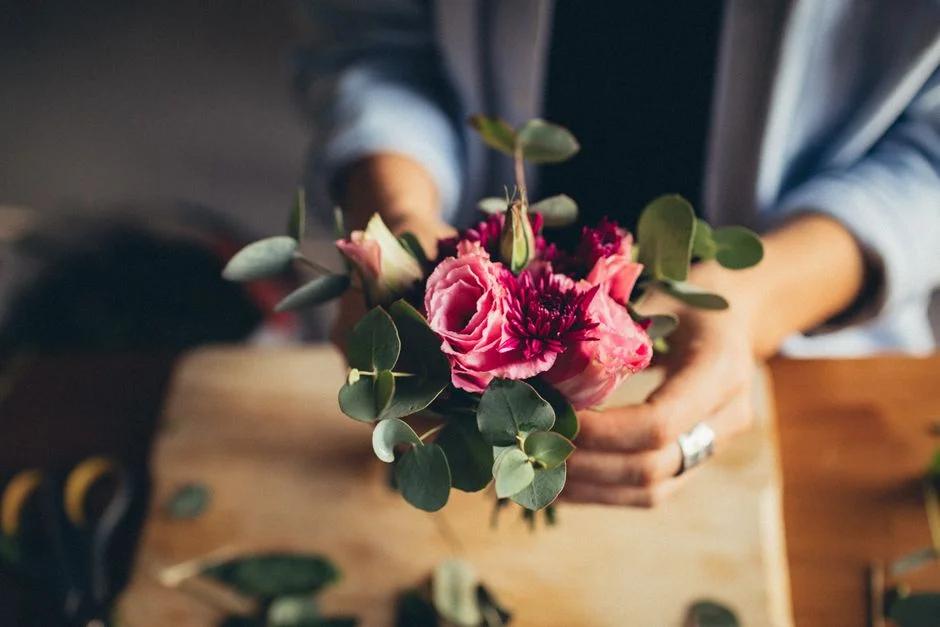 Hands arranging flowers at a workshop table